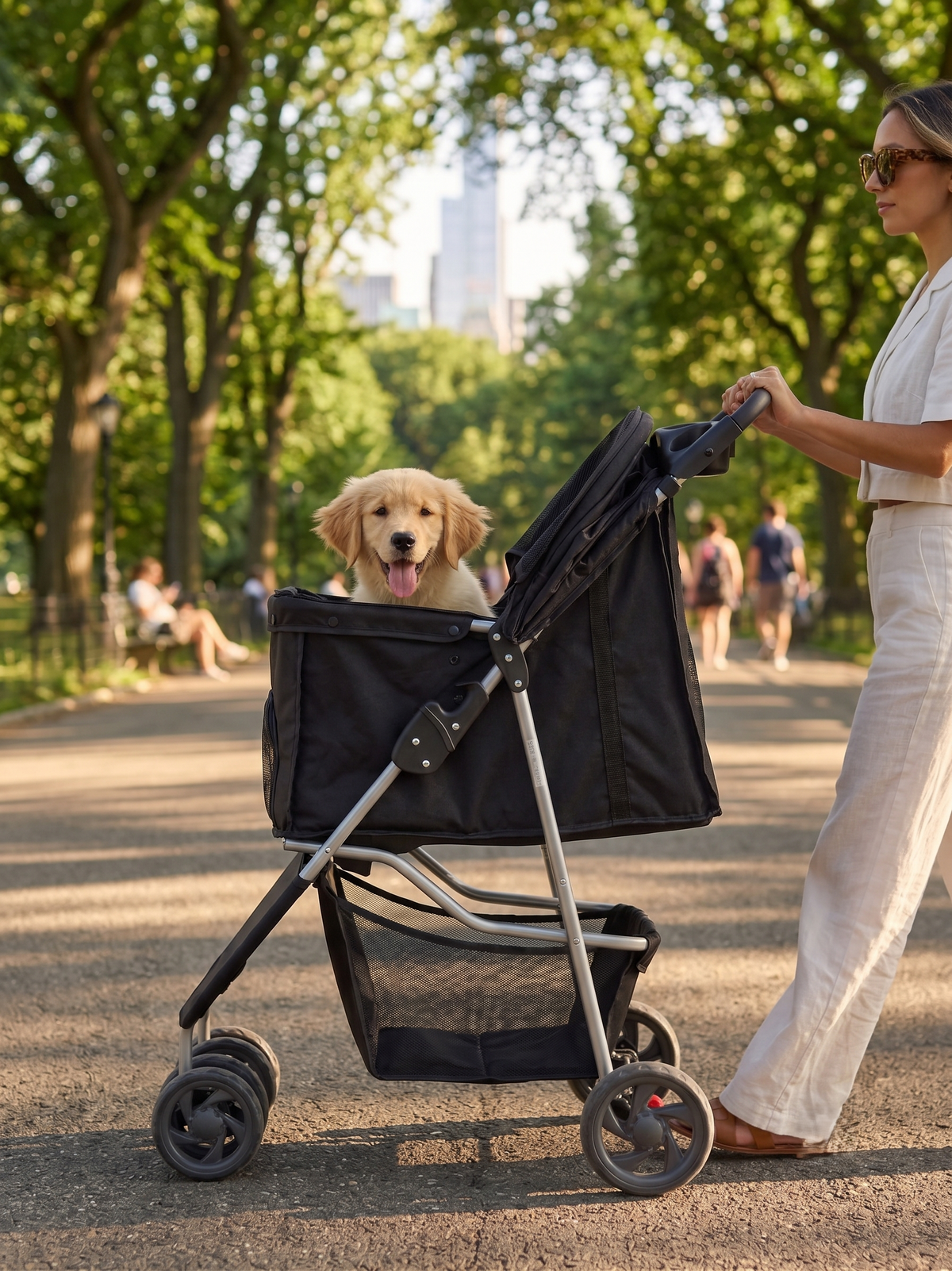 GianfiStore foldable pet stroller in Central Park New York — golden retriever puppy inside, woman in white linen outfit, tree-lined path