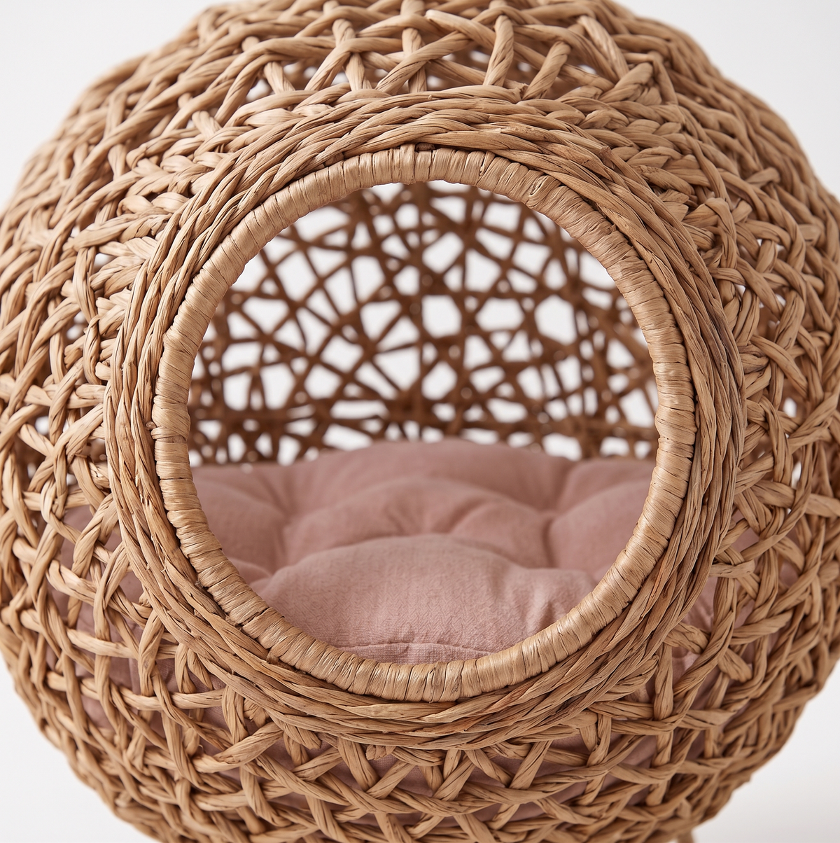Close-up of the entrance opening of the water hyacinth cat bed, showing the hand-woven weave and cushioned interior