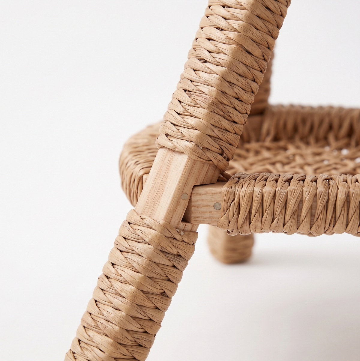 Close-up of the tripod leg and joint construction of the water hyacinth cat bed, showing hand-wrapped wicker detail on white background