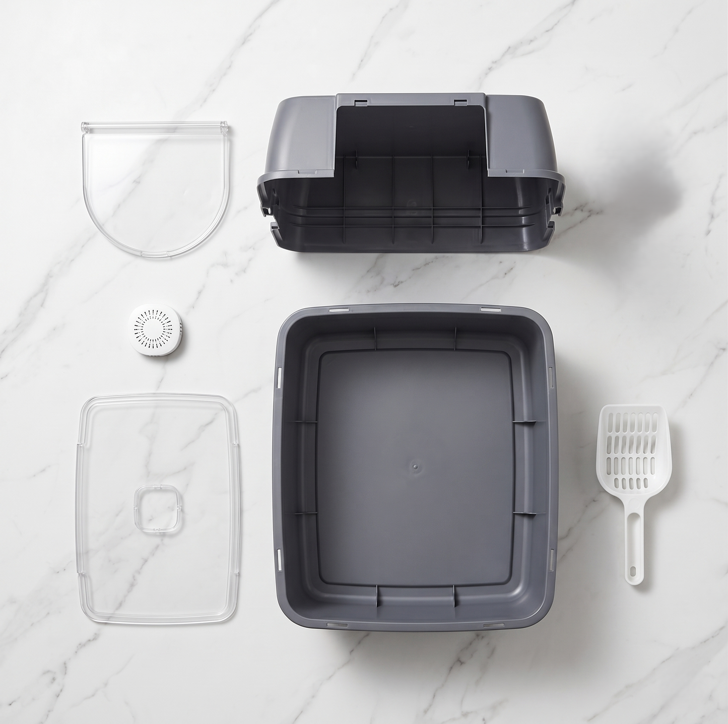 Enclosed cat litter box fully disassembled showing all components: top cover, transparent door flap, transparent bottom tray, odor filter, litter scoop on white marble surface