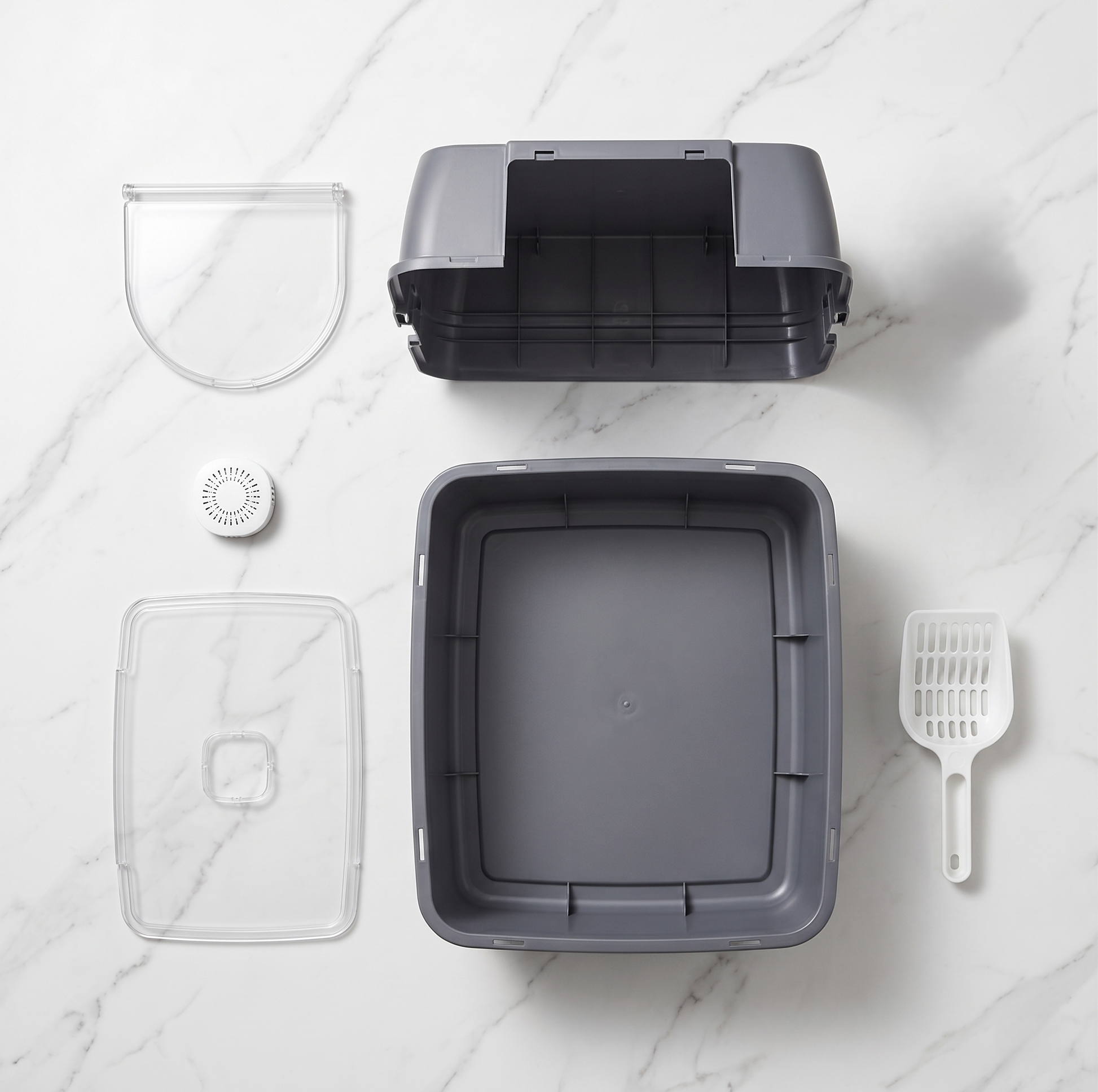 Enclosed cat litter box fully disassembled showing all components: top cover, transparent door flap, transparent bottom tray, odor filter, litter scoop on white marble surface